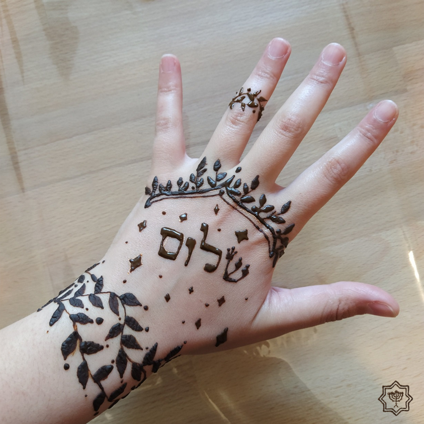 Dessin au henné sur la main par Sandra Yerushalmi écrit "Shalom" en hébreu